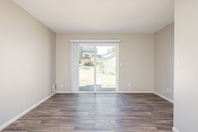 Tigard apartment for rent - A room with wooden floors and a sliding glass door leading outside.