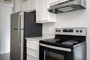 Milwaukie apartment for rent - A black stove top oven with a digital display and a silver refrigerator in a kitchen.
