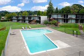 Portland apartment for rent - A large swimming pool in a fenced in area with a building in the background.