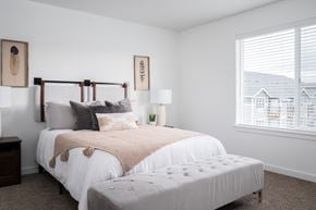 Oregon City townhouse for rent - a bedroom with a bed and an ottoman in front of a window