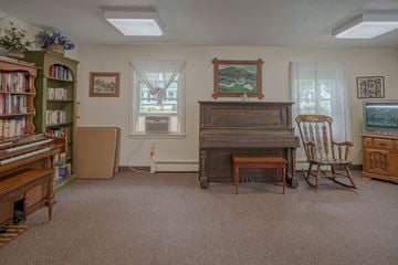 Colebrook apartment for rent - a living room with a piano and a bookshelf filled with books