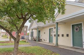 Littleton apartment for rent - the front of a yellow house with a green door and a tree