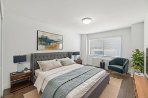 Washington apartment for rent - A bedroom with a large bed, a green chair, and a painting on the wall.