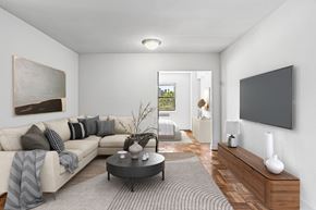 Washington apartment for rent - A modern living room with a grey couch, a coffee table, and a flat screen TV mounted on the wall.