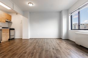 Washington apartment for rent - A spacious room with wooden flooring and a window overlooking a cityscape.
