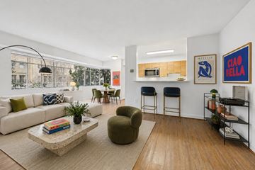 Washington apartment for rent - A living room with a white couch, a green chair, and a coffee table with a book on it.