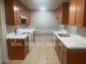 Stockton triplex for rent - a kitchen with marble counter tops and wooden cabinets