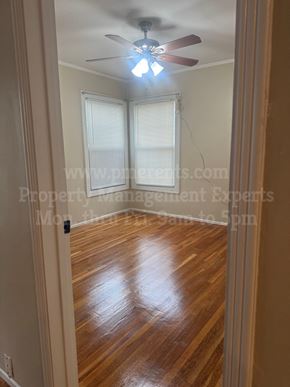 Stockton triplex for rent - A room with a ceiling fan and wooden flooring.