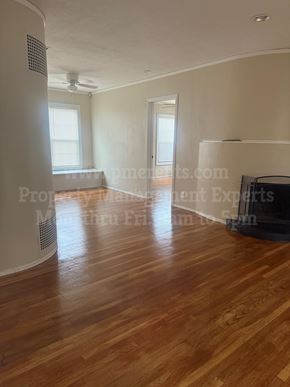 Stockton triplex for rent - A room with wooden floors and a ceiling fan.