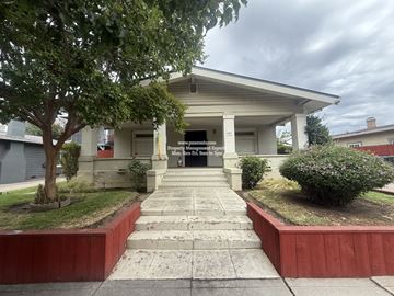 Stockton apartment for rent - A white building with a porch and a tree in front.