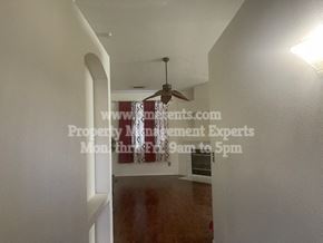 Stockton apartment for rent - a hallway leading to a living room with a ceiling fan