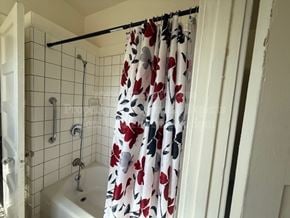 Stockton apartment for rent - A shower curtain with a floral pattern hangs over a bathtub.