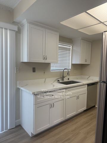 Stockton triplex for rent - A kitchen with white cabinets and a stainless steel refrigerator.