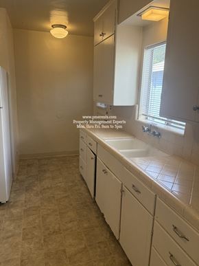 Stockton triplex for rent - A bathroom with a tiled floor and white cabinets.