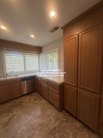 Stockton apartment for rent - A kitchen with wooden cabinets and a window with blinds.