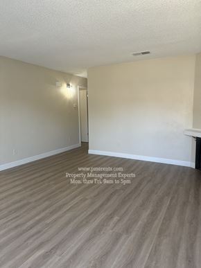 Stockton triplex for rent - A room with a wooden floor and a door on the left side.