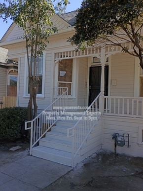 Stockton apartment for rent - A house with a porch and a tree in front.