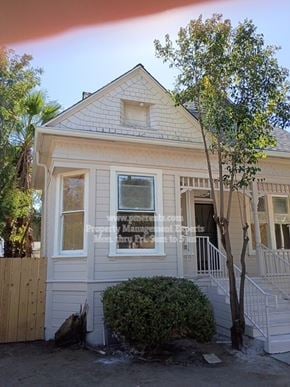 Stockton apartment for rent - A house with a white facade and a tree in front.