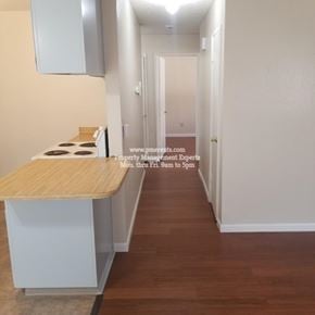 Modesto condo for rent - A long hallway with a wooden floor and white walls.