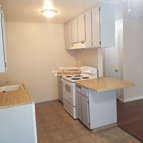 Modesto condo for rent - A kitchen with white cabinets and a wooden countertop.