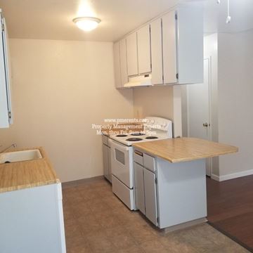 Modesto condo for rent - A kitchen with white cabinets and a wooden countertop.