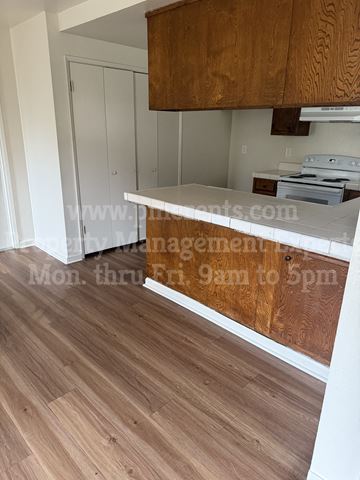 Stockton triplex for rent - A kitchen with a white countertop and wooden cabinets.