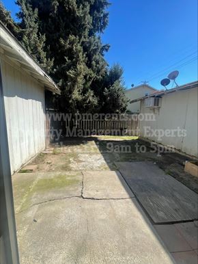 Stockton triplex for rent - A backyard with a concrete patio and a white fence.