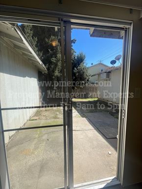Stockton triplex for rent - A view from inside a room looking out through a sliding glass door.