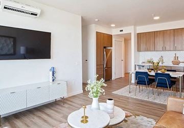 Vancouver apartment for rent - A living room with a white sofa, a television, and a dining area with a table and chairs.
