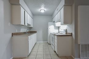 Pleasanton apartment for rent - an empty kitchen with white cabinets and a white refrigerator at Eagle View Apartments, Texas