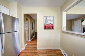 Overland Park apartment for rent - A kitchen with a refrigerator on the left and a painting of a building on the wall.