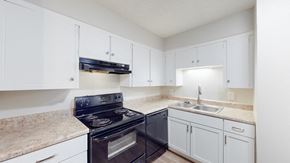Kansas City apartment for rent - A kitchen with a black stove top oven and white cabinets.