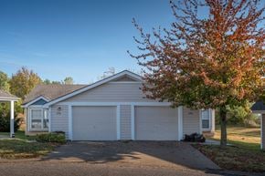 Lawrence townhouse for rent - A house with a white garage door is in front of a tree with red leaves.