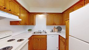 Kansas City apartment for rent - A kitchen with wooden cabinets and white appliances.