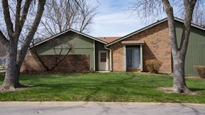 Lawrence townhouse for rent - A house with a green roof and a brick exterior is surrounded by trees.