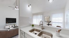 Olathe apartment for rent - A modern kitchen with a double sink and a ceiling fan.
