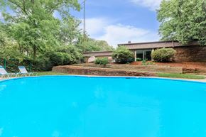Lafayette apartment for rent - A swimming pool surrounded by trees and a building in the background.