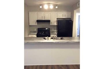 Bloomington apartment for rent - A black refrigerator sits in a kitchen with white cabinets.