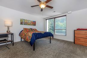 Lafayette apartment for rent - A bedroom with a bed, a desk, a chair, a ceiling fan, and a window with blinds.