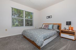 Bloomington apartment for rent - A bedroom with a bed, nightstand, and window.