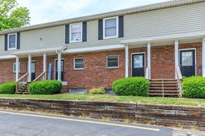 Bloomington apartment for rent - A red brick house with a porch and a white roof.