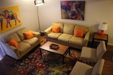 Bloomington apartment for rent - A living room with a couch, chair, and a painting on the wall.