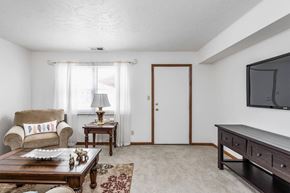 Bloomington apartment for rent - A living room with a couch, a coffee table, a lamp, a rug, a door, and a television.