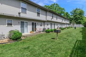 Bloomington apartment for rent - A row of houses with green lawns and trees in the background.