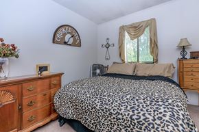 Lafayette apartment for rent - A leopard print bed sits in a bedroom with a wooden dresser and a cross hanging on the wall.