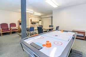 Lafayette apartment for rent - A shiny air hockey table is in the middle of a room with chairs and a kitchen in the background.