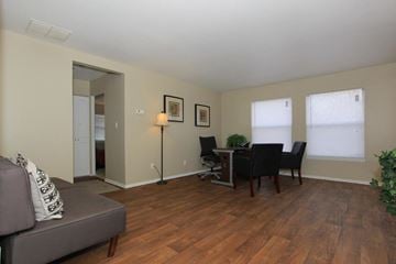 West Lafayette apartment for rent - A living room with a grey couch, a dining table with chairs, and a lamp.