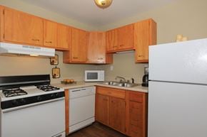 West Lafayette apartment for rent - A kitchen with wooden cabinets and white appliances.