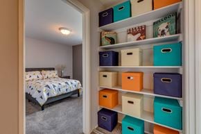 Lansing townhouse for rent - A bedroom with a bed and a shelf with storage boxes.