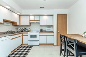Dekalb apartment for rent - A kitchen with white cabinets and a black and white checkered rug.
